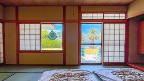 A traditional Japanese room with tatami flooring, shoji screens, and a view of a beach. - Seatiger Island In Shodoshima (Shodoshima)