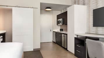 Une chambre d’hôtel moderne équipée d’un lit, d’un bureau, d’un four à micro-ondes et d’une télévision.