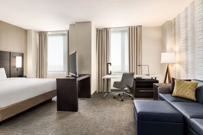 A hotel room with a large bed, a desk, a chair, a sofa, and a TV. - Residence Inn by Marriott New York JFK Airport (Jamaica)