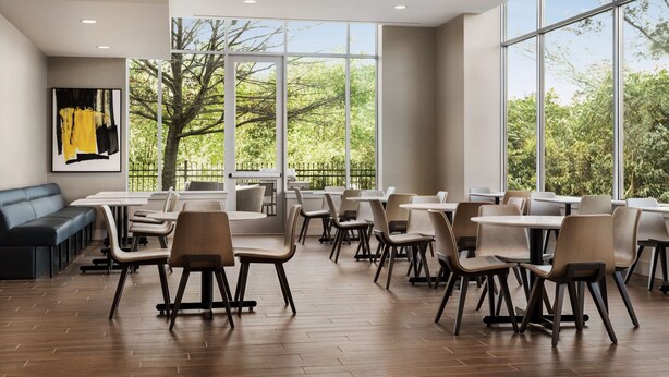 Un comedor amplio con ventanas grandes, piso de madera y una variedad de mesas y sillas.