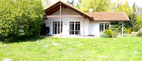 A two-story house with a sloped roof, large windows, and a well-maintained lawn.