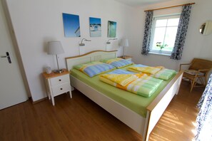 A bedroom with a bed, bedside tables, a chair, and a window with curtains.