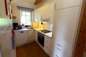 A compact kitchen with white cabinets, a dishwasher, and a stove.