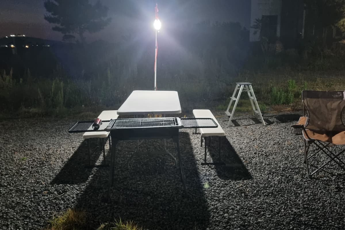 Un espace de camping en plein air équipé d’un barbecue, de chaises et d’une table.