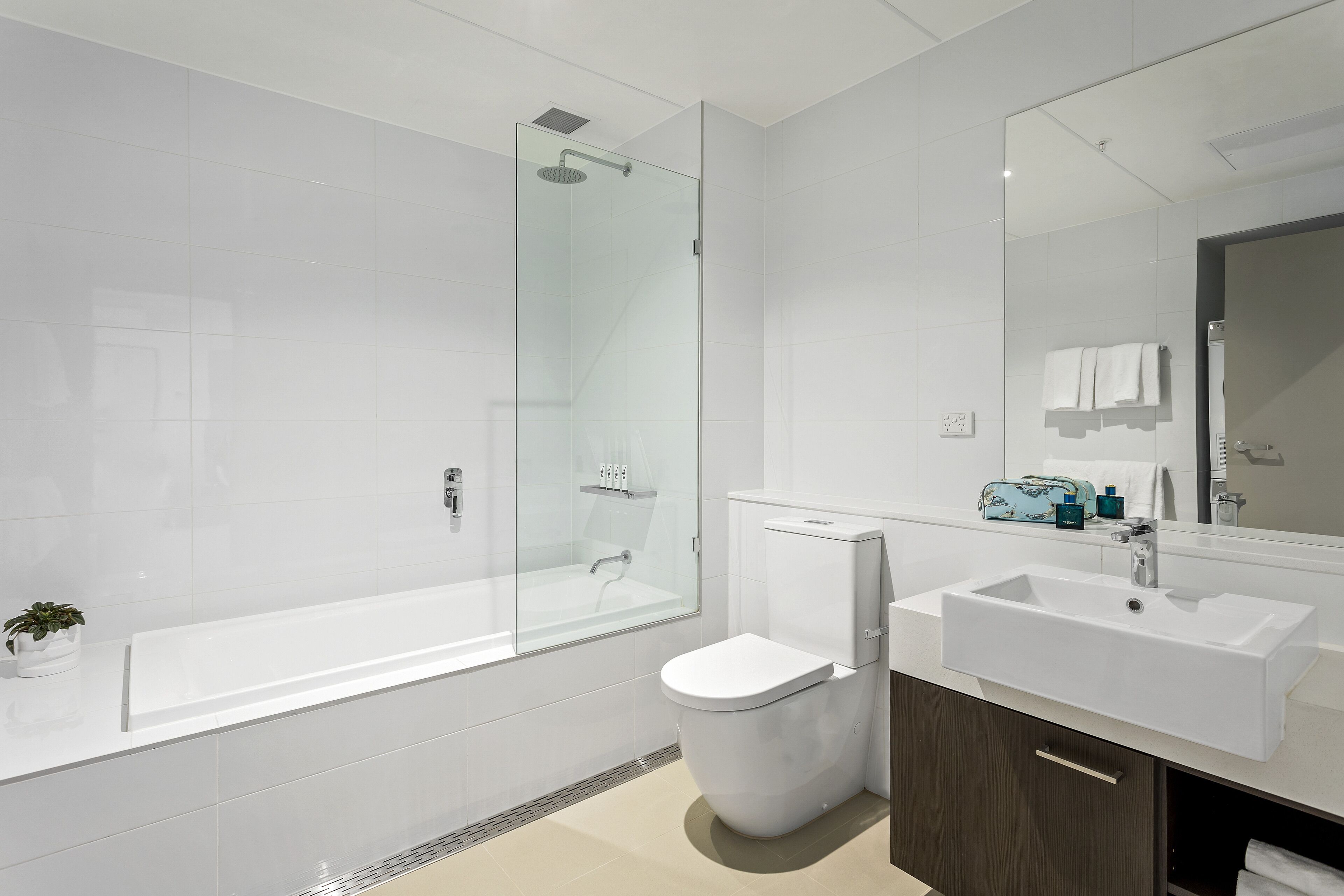 A modern bathroom with a glass-enclosed shower, a white toilet, a sink, and a mirror.