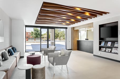 A modern lobby with seating areas, a reception desk, and a large TV screen.