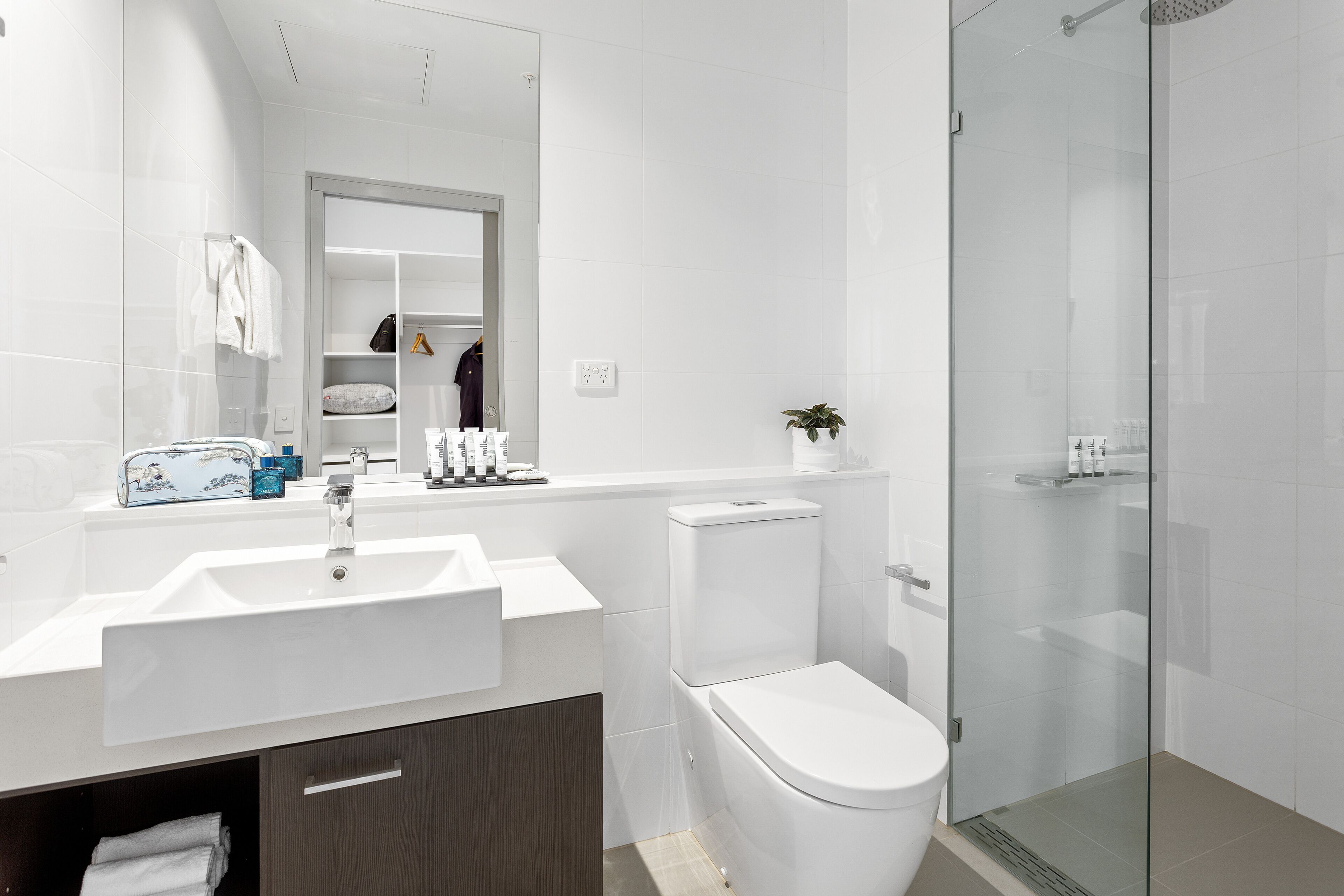 A modern bathroom with a white sink, toilet, and glass shower enclosure.