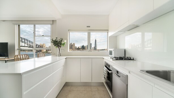 Una cocina moderna con armarios blancos, un ventanal con vista a la ciudad y un horno empotrado.