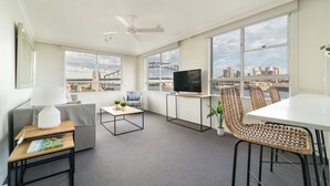 Una sala de estar moderna con un sofá, una mesa de centro, un televisor y un comedor con sillas.