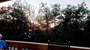 A wooden bench with a lattice backrest, overlooking a forested area with trees and a sunset in the background. - New construction! 1 BD/2 BA Top of Wintergreen mountain. Sleeps 4, pet-friendly (Roseland)