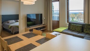 Une chambre d’hôtel avec un lit, une télévision, une table à manger et un canapé.