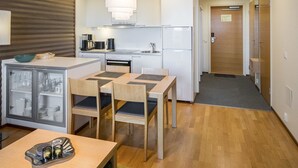 Une cuisine compacte avec un coin repas, comprenant une table avec des chaises, un réfrigérateur, une cuisinière et un four à micro-ondes.
