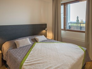 Un lit avec une tête de lit matelassée, deux oreillers et une lampe de chevet.