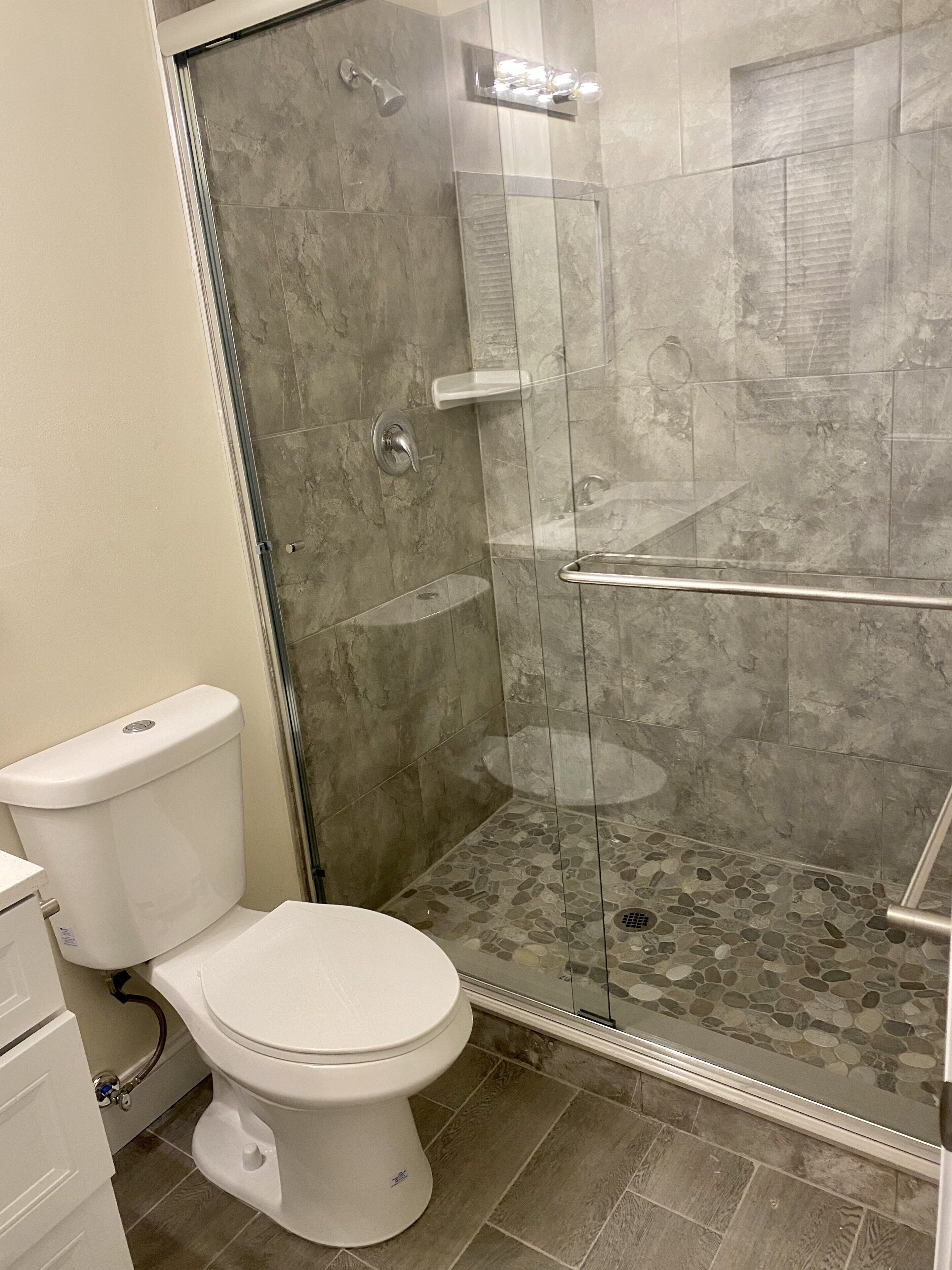 A bathroom with a toilet, a shower with a glass door, and a tiled floor.