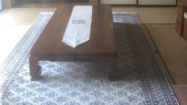 A traditional Japanese room with tatami flooring, a low wooden table, a sliding door, and a hanging scroll on the wall. - Minshuku Tomato House (Tamura)