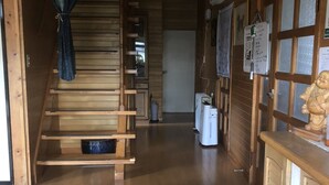 A wooden interior with a staircase, a reception desk, and a sign reading "Tomato House". - Minshuku Tomato House (Tamura)