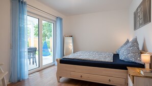 Une chambre à coucher comprenant un lit, une table de chevet, une lampe et une vue sur l’extérieur grâce à une porte-fenêtre coulissante.