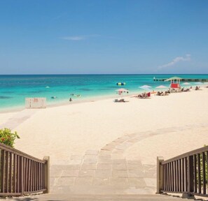 A beach with a lifeguard tower, umbrellas, and lounge chairs.