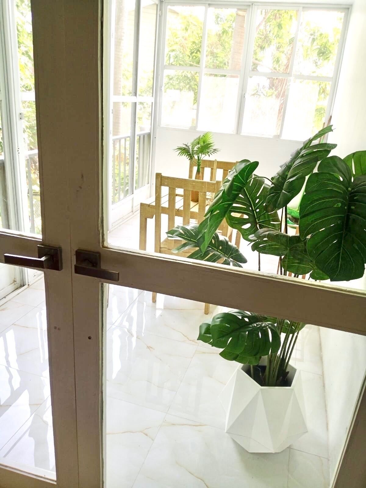Una habitación con un ventanal grande, una silla de madera y una planta en maceta.