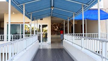 A covered walkway with a patterned floor, white railings, and a blue roof structure.