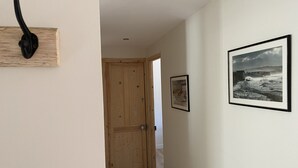 A hallway with a wooden door, a black door handle, and a framed picture on the wall. - Newly renovated 80 m2 luxury apartment (Wimereux)