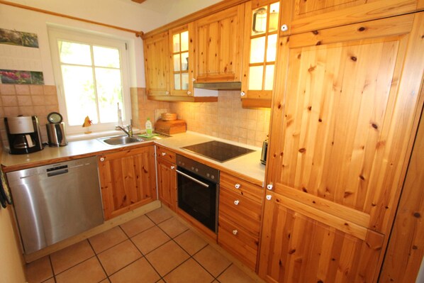 A kitchen with wooden cabinets, a dishwasher, a sink, and a window with natural light.