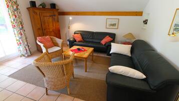 A living room with a sofa, two chairs, a coffee table, and a wooden cabinet.