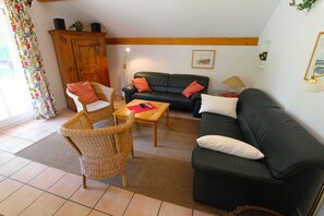 A living room with a sofa, two chairs, a coffee table, and a wooden cabinet.