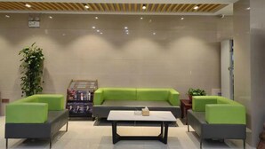 Un hall d’entrée moderne avec un canapé vert, une table basse et une plante.