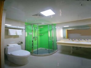 Une salle de bain avec une douche à parois de verre, des toilettes et un lavabo avec un miroir au-dessus.