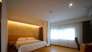 Une chambre d’hôtel avec un grand lit, un bureau et une fenêtre avec des rideaux.