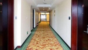 A hotel hallway with a carpeted floor, wooden doors, and a light-colored wall. - Greentree Inn Rizhao Shanhaitian Holiday Resort Bu (Rizhao)