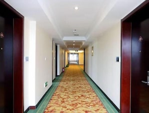 A hotel hallway with a carpeted floor, wooden doors, and a light-colored wall. - Greentree Inn Rizhao Shanhaitian Holiday Resort Bu (Rizhao)