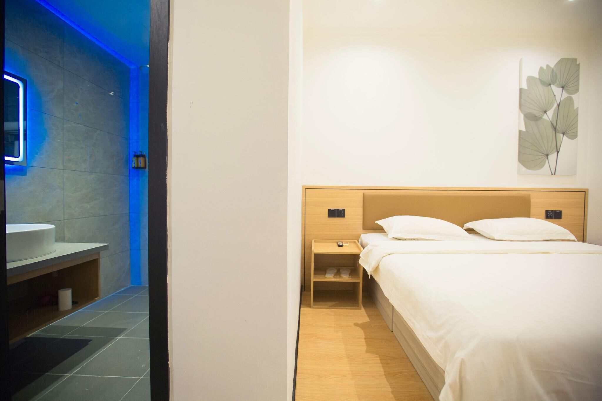 Een hotelkamer met een bed, nachtkastje en een kunstwerk aan de muur.