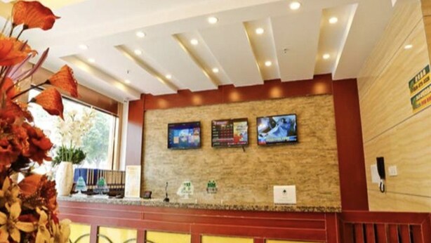 A reception area with a stone wall, three monitors, and a wooden panel on the right.