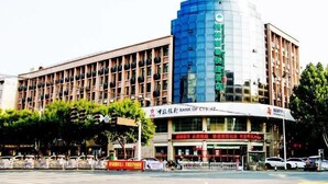 A multi-story building with a prominent blue glass facade and a sign indicating it is a bank.