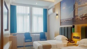 A hotel room with two beds, a desk, a chair, and a window with curtains.