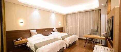 A hotel room with two beds, a desk, and a TV.