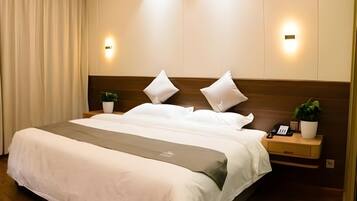 A neatly made bed with white linens, two bedside tables with lamps, and a potted plant on each.