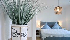 Een slaapkamer met een bed, nachtkastjes en een hanglamp.