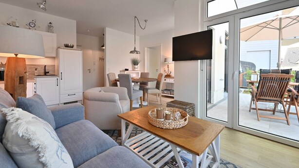 Een moderne woonkamer met een bank, een houten salontafel en een eethoek met stoelen en een tafel.