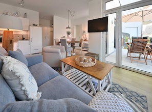 A modern living room with a sofa, a wooden coffee table, and a dining area with chairs and a table.