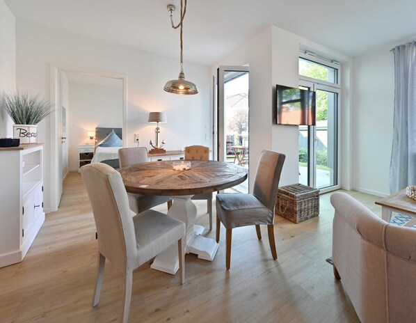 A modern dining area with a round wooden table, white chairs, and a hanging pendant light.