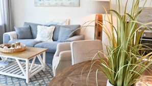 Een woonkamer met een bank, fauteuils, een salontafel en een potplant.