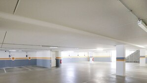 Un vaste espace de stationnement intérieur, doté d’un éclairage au plafond clair, de places de stationnement délimitées et d’un pilier central.