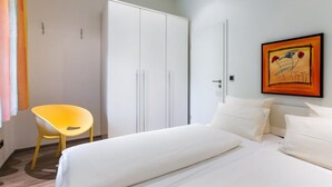 Une chambre d’hôtel avec un lit, une chaise, une armoire et un tableau au mur.