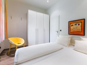 Ein Hotelzimmer mit Bett, Stuhl, Kleiderschrank und einem Bild an der Wand.