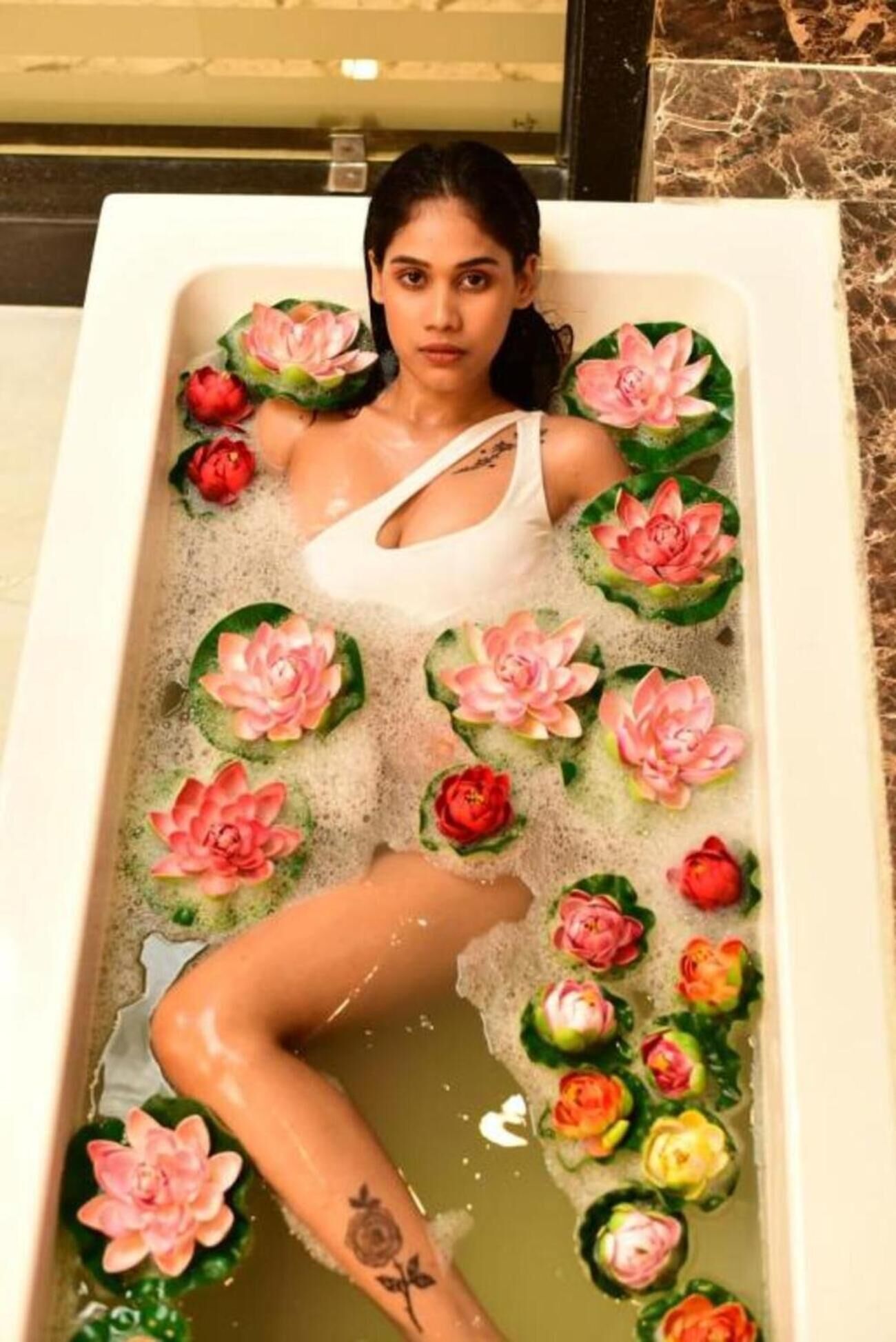 A bathtub with floral decorations and a person lying in it.
