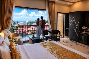 Quarto de hotel com varanda, cama, escrivaninha e guarda-roupa.