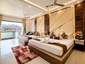 A modern hotel room with a large bed, two bedside tables, a sofa, a red and beige rug, and a view of the outside.